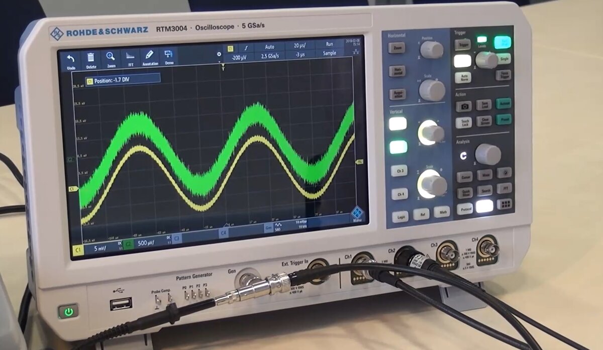 Как вы видите формы сигналов на первом и втором канале осциллографа совпадают, но они не идентичны. Для наглядности активируем режим огибающей при захвате данных.

Напомним, что на входы измерительных трактов канала 1 и канала 2 подавался один и тот же сигнал, но из-за различия в измерительных трактах при отображении мы получили различные результаты.
Самый сильный эффект, который виден невооружённым глазом-это то, что сигнал по каналу 2 там, где используется пробник, более зашумлён. Этот результат ожидаем, ведь в данном случае мы использовали пробник с делителем 10:1 и его чувствительность заведомо ниже, чем при прямом подключении. Несмотря на это, пробники с делением 10:1 являются одними из самых распространённых, так как расширяют диапазон входных каналов осциллографа по амплитуде в 10 раз.
 Мы только что наглядно Вам продемонстрировали, что любой реальный измерительный пробник будет вносить в передаваемый сигнал искажения.
Именно достоверность передачи сигнала из контрольной точки на вход осциллографа и является тем параметром, который определяет качество пробника и возможности его работы. 
Исследователь в своей работе всегда старается использовать тот пробник, который будет вносить минимальные искажения и наиболее достоверно передаст сигнал на вход.
Именно по этой причине практически все производители в комплекте с осциллографов поставляют измерительные пробники. Так пробники компании R&S разрабатываются как неотъемлемая часть измерительного тракта осциллографов и благодаря этому имеют высокую степень согласования с прибором, что обеспечивает низкий уровень вносимых ими искажений.