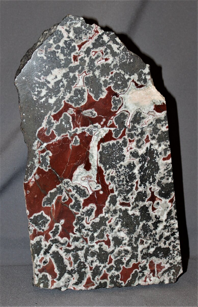 Порода имеет вулканическое происхождение (трахибазальт), которая после образования подверглась дроблению с последующей гидротермальной цементацией кальцитом.-3