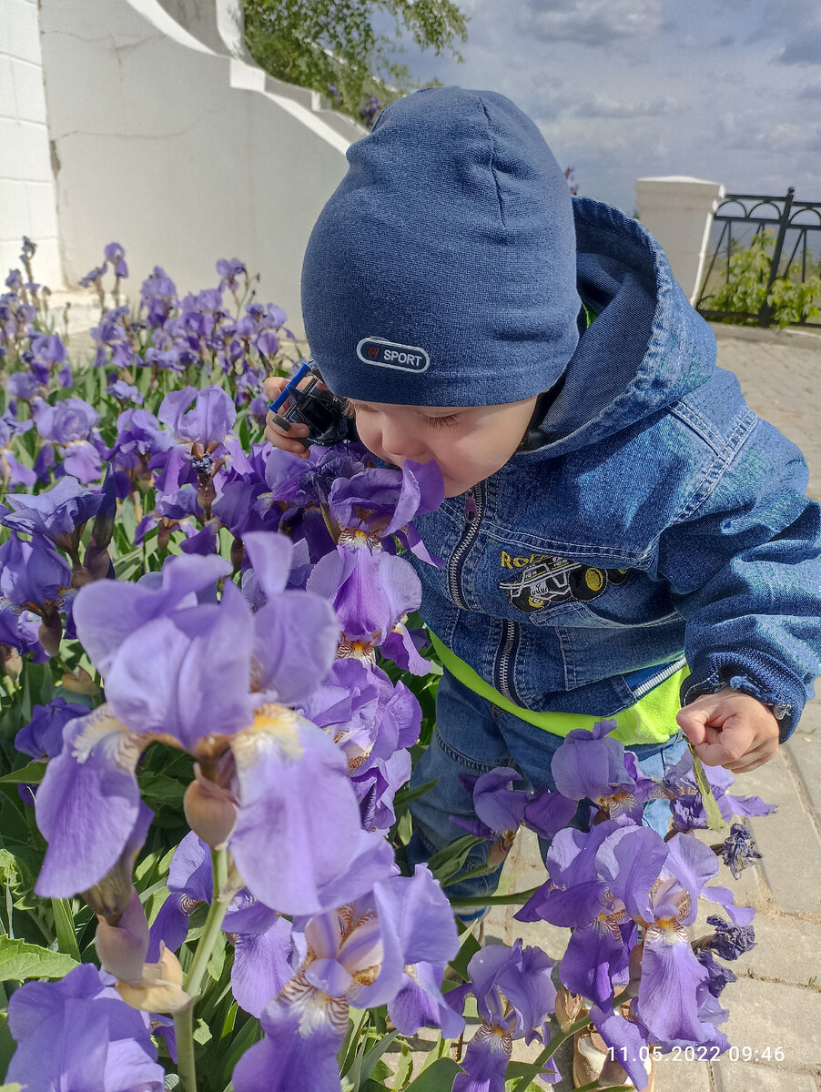 Андрюша нюхает цветы возле мемориала. 