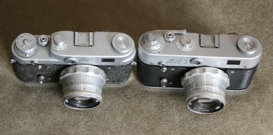 Фотоаппараты ФЭД-3, модификации до и после 1966 года. На правом виден курковый взводной рычажок. 