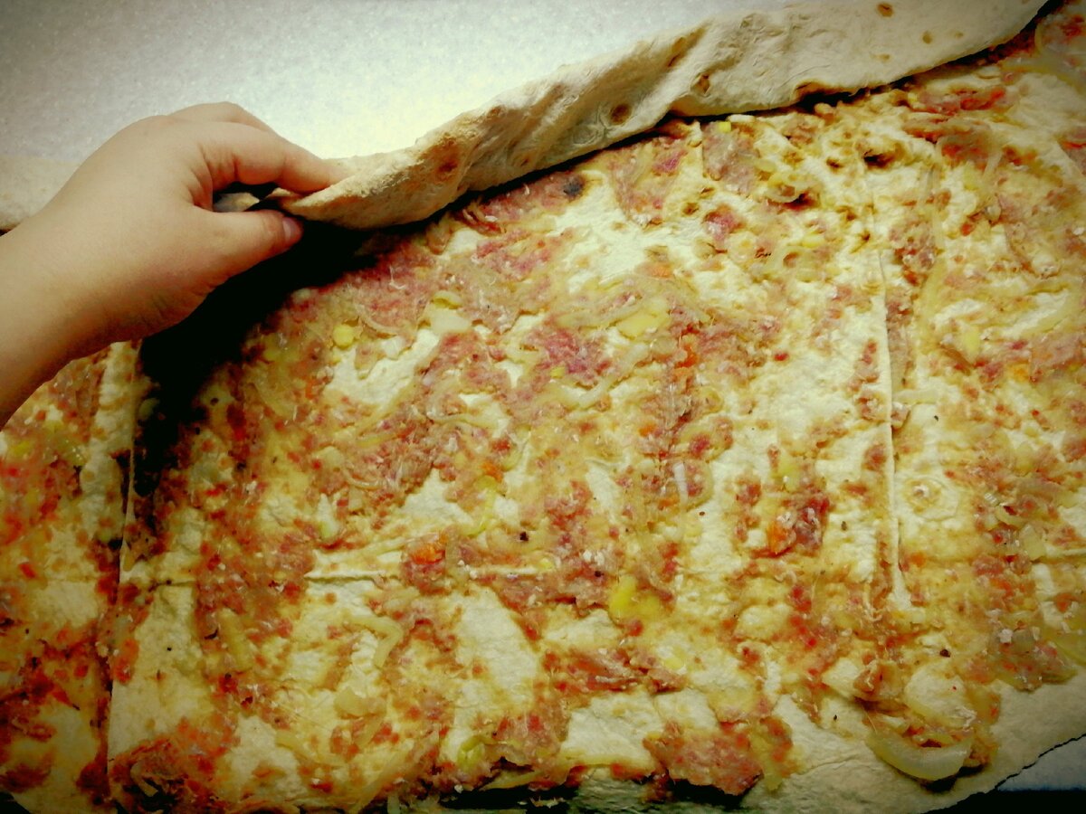 Распределили фарш по лавашу и скручиваем его в рулетики.