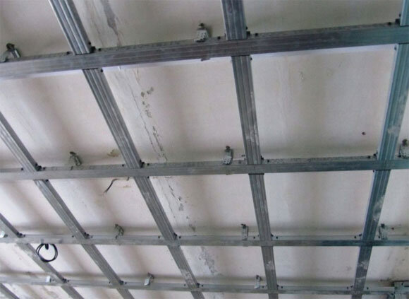 Устройство гипсокартонного потолка представляет собой жестко закрепленный на потолке и стенах металлический каркас, который снизу обшивают гипсокартонными листами, как он выглядит, видно на фото. Для создания основы конструкции используют специальный профиль, производимый из оцинкованного металла, его подвешивают на жестком подвесе к базовому потолочному перекрытию или применяют подвес из прутьев, имеющий специальные кронштейны. 