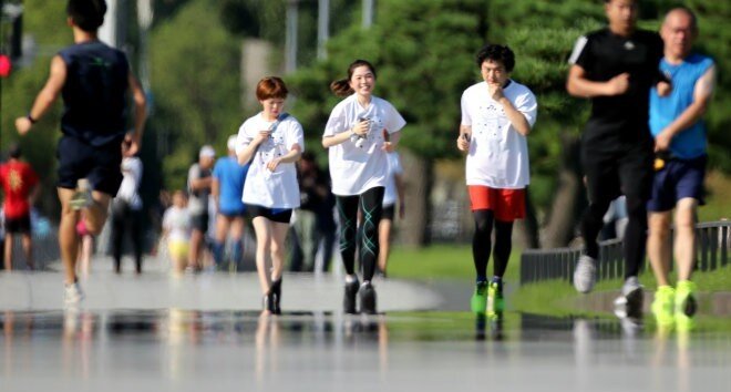 Бегуны, бегающие трусцой перед историческим мостом Нидзубаши Императорского дворца в районе Тиёда в Токио 9 августа, сталкиваются с миражом. Дорога станет частью марафонской дистанции Олимпийских игр в Токио в 2020 году. 