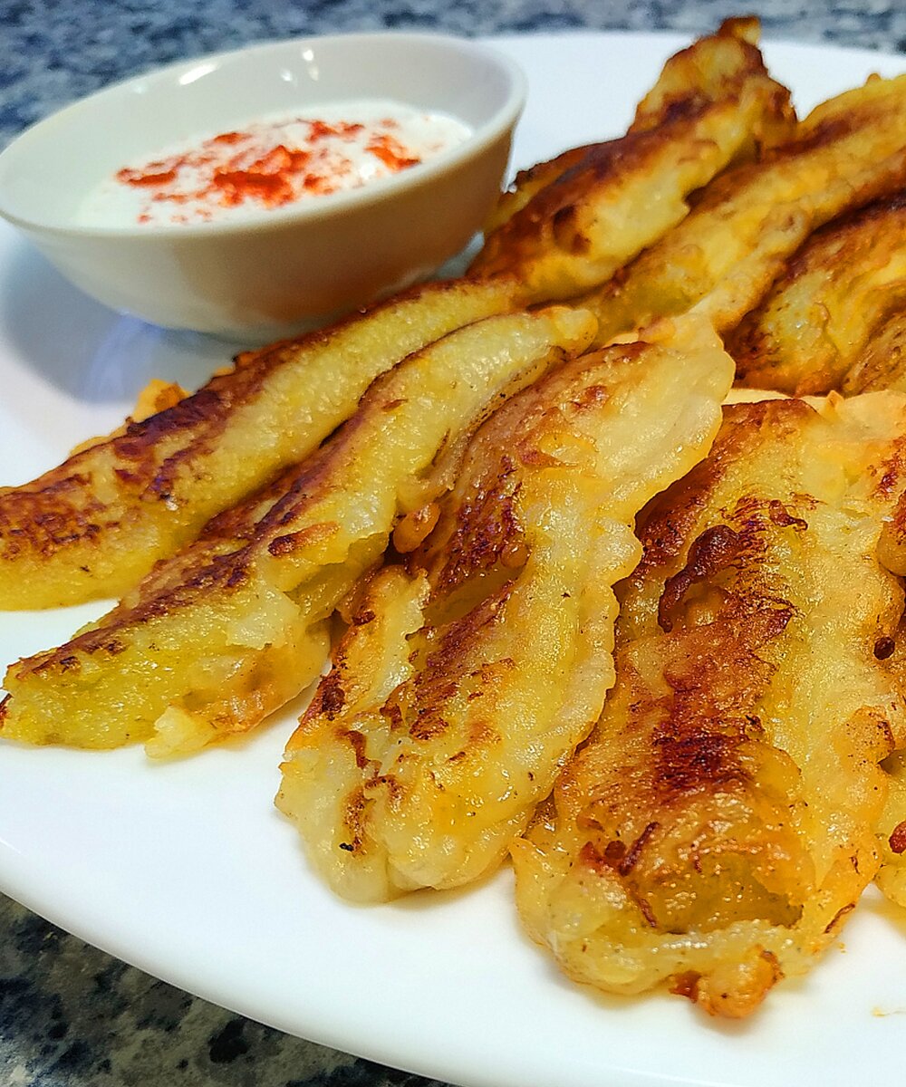 Аппетитные, хрустящие и очень вкусные бананы в кляре по-индийски. Подаются горячими, сметана с перцем чили по вкусу. 
Ингредиенты:
бананы - 4 шт. не слишком спелые
яйцо - 1 шт.
мука - 4 ст.л.
кардамон молотый - 0.5 ч.л.
сахар - 2 ст.л.
соль - 1/4 ч.л.
растительное масло - 2 ст.л. в кляр
вода - 50-80 мл. 
растительное масло для жарки - 80-100 мл.
Сметана и перец чили по вкусу.
1. Бананы очистить и разрезать на четыре части.
2. Приготовить кляр. В муку добавить сахар, соль и молотый кардамон, перемешать венчиком. Затем добавить яйцо, растительное масло и воду. Воду добавляйте по немногу, кляр должен получиться слегка густоват. 
3. Разогреть растительное масло на сковороде. 
4. Окунуть бананы в кляр, стряхнуть лишнее. Обжаривать на среднем огне по 2-3 минуты до румяной корочки с каждой стороны.
Подавать горячими. Сметана с перцем чили по вкусу.