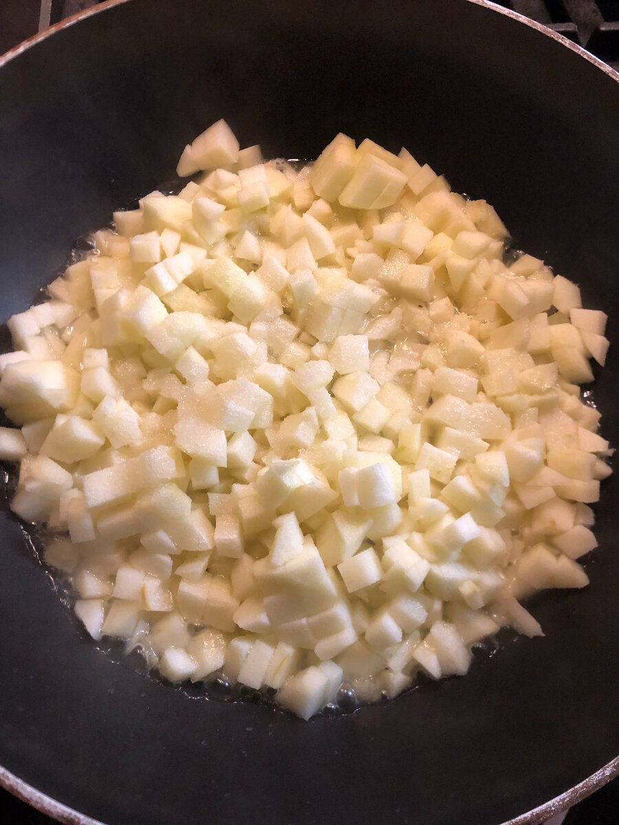 В сковороду положить небольшой кусочек сливочного масла и добавить мелко порезанные яблоки и добавить сахар. 