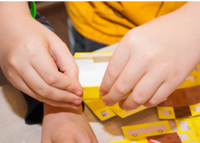 Ребенок отвлекся от компьютерной игры Майнкрафт и собирает своего героя Стива в золотой броне с магнитами  грушки герои компьютерной игры Майнкрафт  собранные из бумажных схем с магнитами  