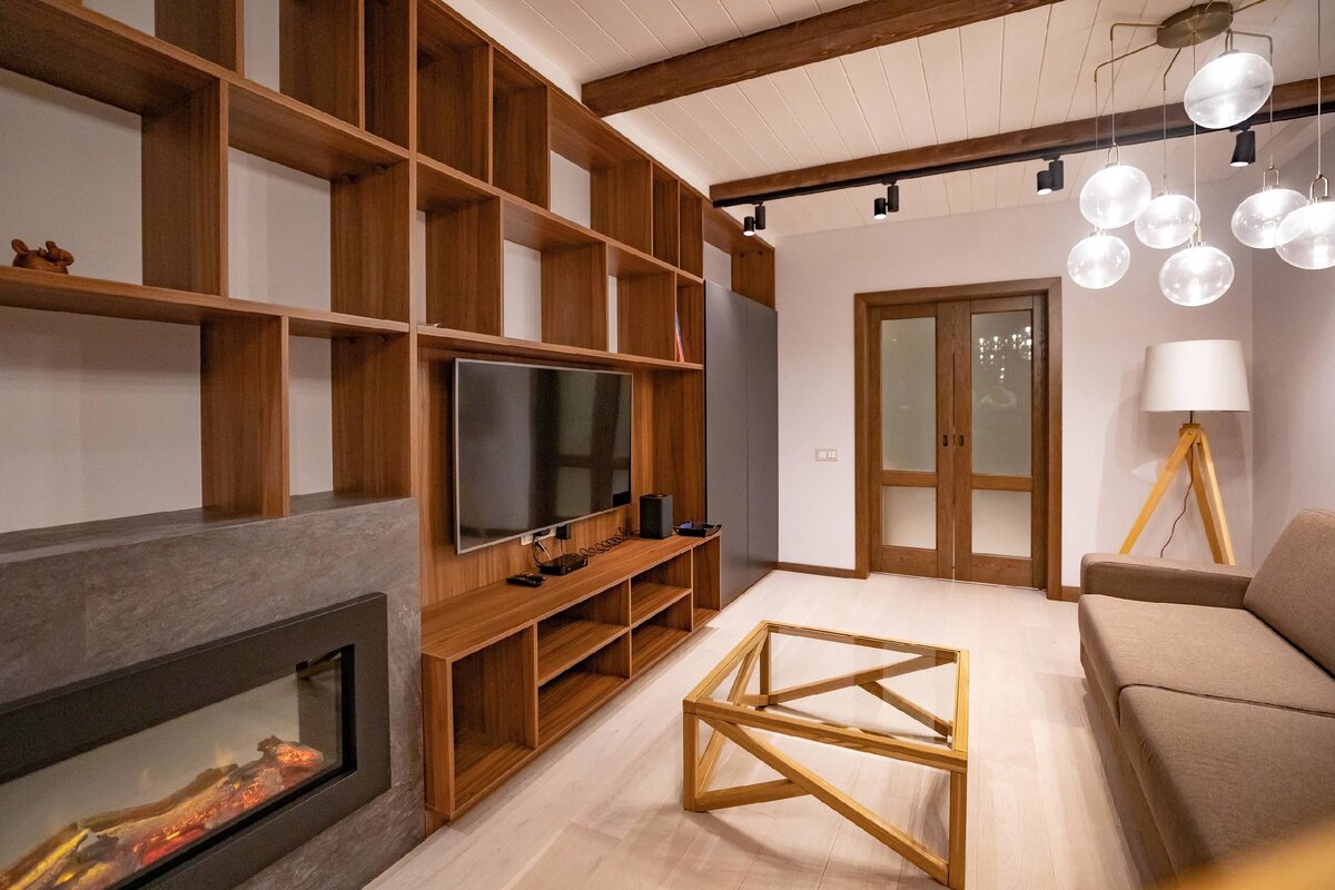 Напротив разместили ТВ-зону со стеллажами и электрокамином.