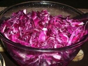     Вымойте краснокочанную капусту для салата. Нарежьте её тонкой соломкой, помните: чем тоньше, тем вкуснее. Для шинкования может подойти кухонный комбайн. Пожмите её руками, для того чтобы она стала сочнее и мягче. После нужно добавить уксус.   