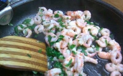     Сковороду поставьте на средний огонь, затем добавьте в нее растительное масло, затем мелко измельченный зубчик чеснока. Немного обжарьте его, но не допустите, чтобы чеснок потемнел. Как только Вы почувствуете его аромат, сразу же добавляйте очищенные креветки. Перемешивайте деревянной лопаткой. В это время мелко измельчите зелень петрушки и также добавьте в сковороду. Лайм или лимон ополосните под холодной проточной водой, затем разрежьте пополам и выдавите в сковороду сок половинки цитруса. Немного поперчите, затем хорошенечко перемешайте. Обжаривайте все до тех пор, пока вся жидкость не выпариться. Это займет не больше нескольких минут.    