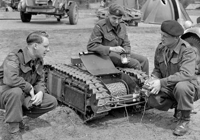 Британские солдаты рассматривают пленительный электрический Голиаф, замечают барабан с проволочным контрольным проводом и элементы управления в руках солдата слева