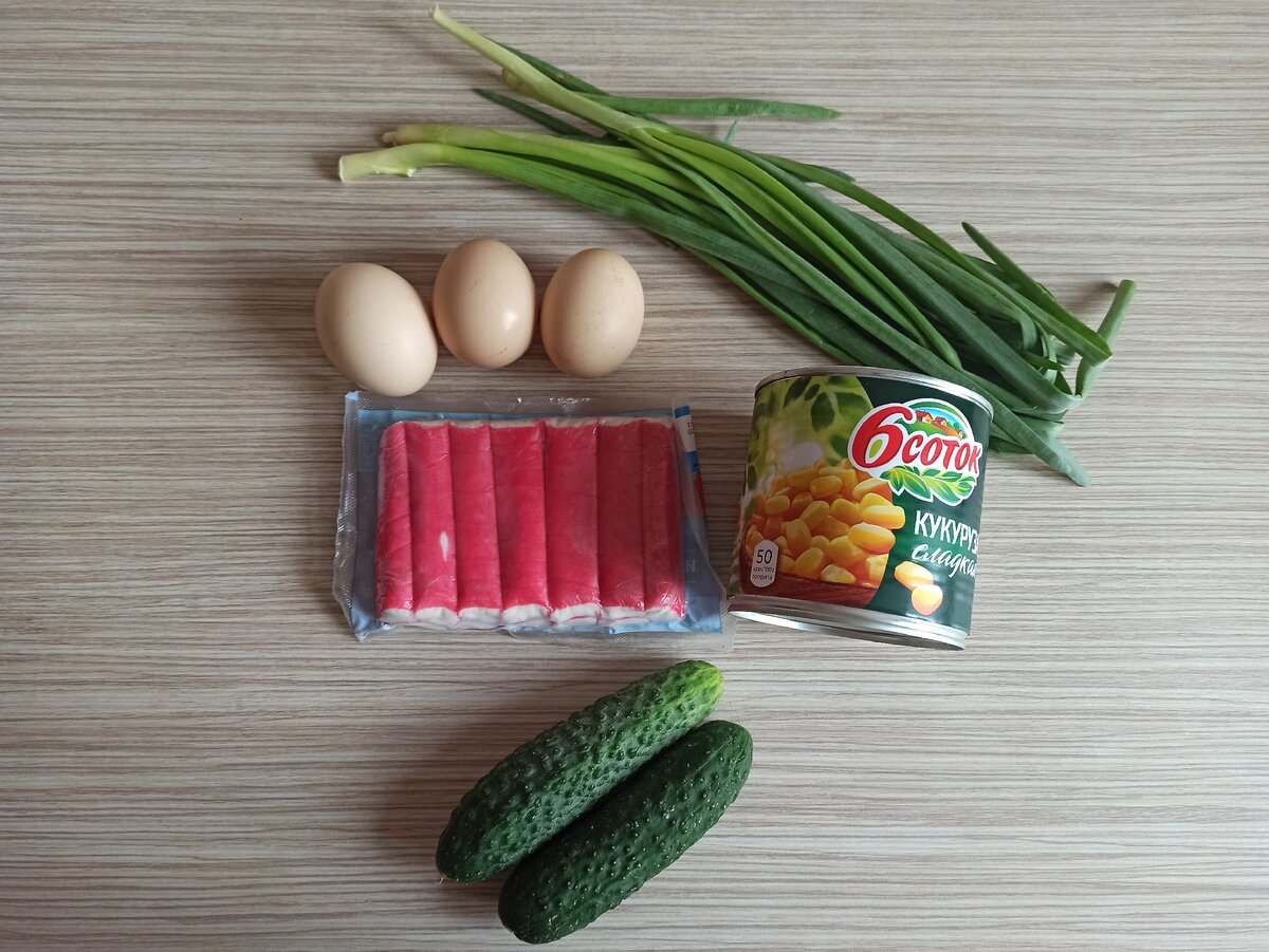 Нам понадобятся 3 вареных яйца, упаковка крабовых палочек, банка кукурузы, 2 свежих огурца, зеленый лук и майонез.