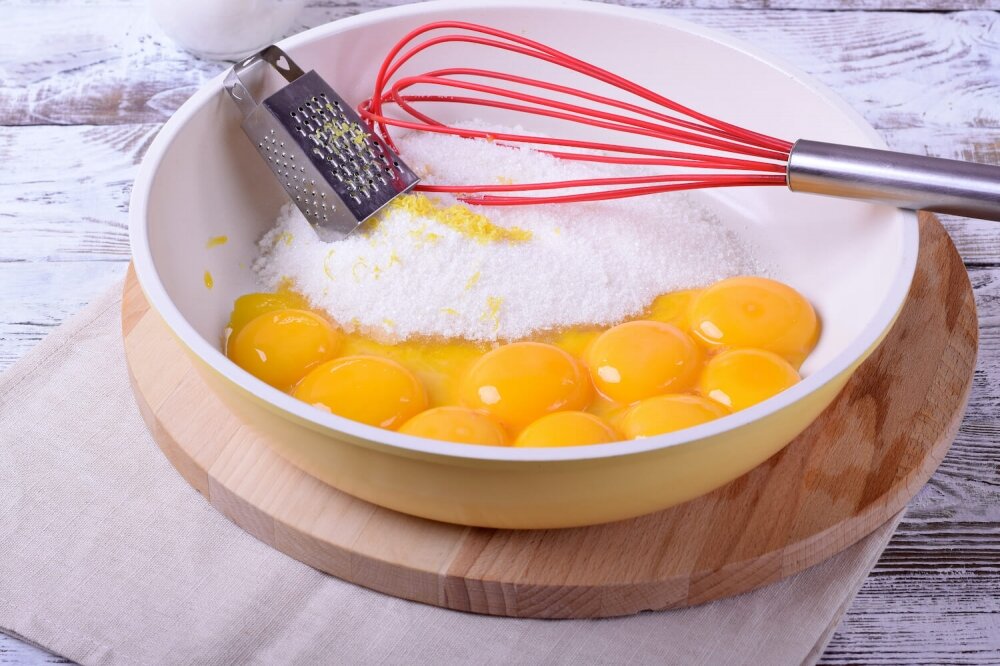 1. If the puff pastry is frozen, from the evening let’s transfer it to the fridge so that it delicately unfreezes. Note that cream is measured not in milliliters, but in grams. Mix sugar with vanillin. Take the zest off the lemon on small grater.

Preparation of cakes begins with preparation of vanilla custard. It can be cooked on a water bath, which will significantly increase the time of dessert preparation. And you can cook it by putting a saucepan on the smallest fire and, stir constantly, control the process so that the custard doesn’t overheat.

So, in a saucepan with a thick bottom pour sugar with vanillin, add egg yolks and lemon zest.