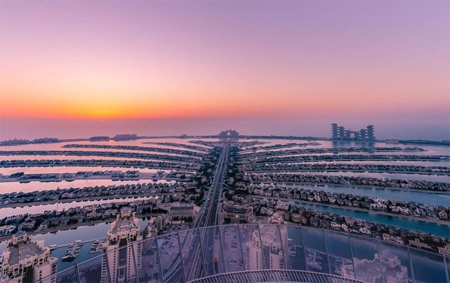 Уникальность Palm Jumeirah заключается в том, что этот остров был создан руками человека. Назван он так не случайно – его форма напоминает ствол пальмы с раскинутой кроной, вокруг которой находится волнорез в форме полумесяца. С материковой зоной остров связан мостом, а полумесяц соединен с ним с помощью подводного туннеля. 
С каждым годом туристов и людей, мечтающих жить на берегу моря именно в Дубае, становится все больше. И в один момент власти столкнулись с проблемой нехватки места на береговой зоне. Тогда и пришла мысль создать рукотворный остров. Строительство Palm Jumeirah позволило увеличить береговую линию более чем на 56 километров и отдать ее под застройку. 

В планах руководителей проекта было строительство жилья на 120 тысяч человек, но все было раскуплено за 3 дня после старта продаж. Поэтому строительство продолжили. 

На центральной части острова, который называют “стволом”, располагаются высотные дома, торгово-развлекательные центры, отели. А на “листьях” – виллы, у каждой из которых есть свой собственный выход к морю. С одной стороны у владельцев недвижимостью на Palm Jumeirah открывается вид на прекрасное море с восхитительными восходами и закатами. А с другой — можно любоваться красотой современного города с его небоскребами. 