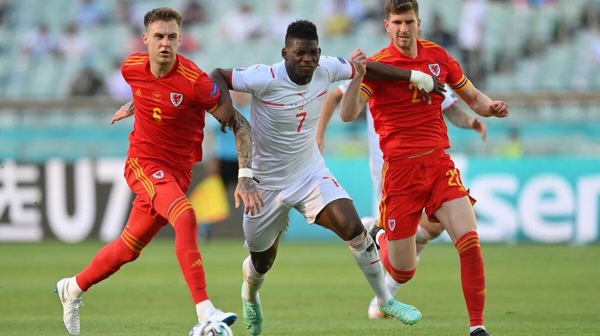 Брил Эмболо в белой форме против игроков Северной Македонии