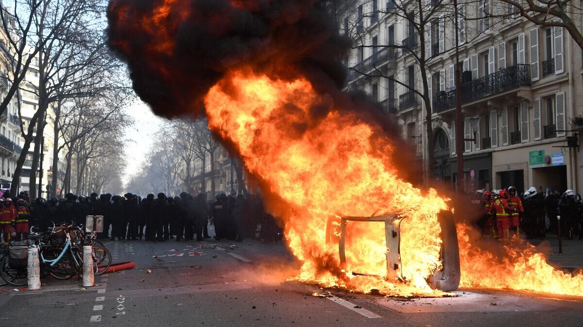    Горящий автомобиль во время акции протеста против пенсионной реформы в Париже© AFP 2023 / Bertrand Guay