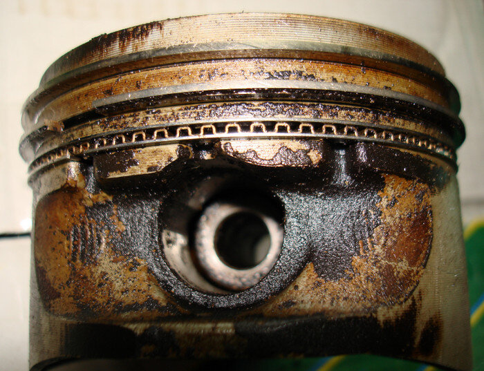 Двигатель начинает троить, и повышается расход топлива. Может снизиться также и мощность двигателя. Многие водители со стажем именно по этому признаку определяют время, когда надо менять кольца. И это правильно, ведь мощность двигателя напрямую зависит от состояния колец. Вся поршневая группа должна обеспечивать необходимый уровень компрессии для того, чтобы двигатель функционировал оптимально. Существует даже специальное значение компрессии, которое в норме должно равняться 9. Износ поршней, поршневых колец Повышенный расход масла, как правило, в большинстве случаев дополняется снижением мощности двигателя.