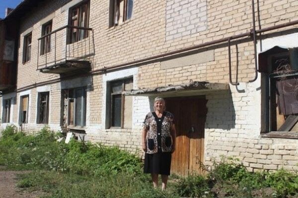 Бабушка Аня на фоне своего дома.