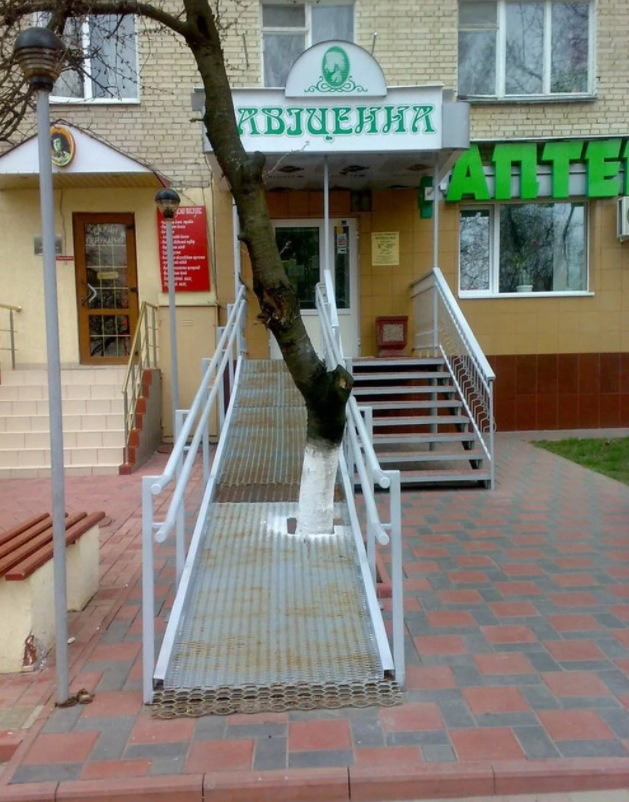 Возможно пандус стоило сделать с правой стороны. Там не мешает дерево и дверь открывается правильно. Но заехать самостоятельно у "колясочника" не получиться с любой стороны, бордюр мешает.   