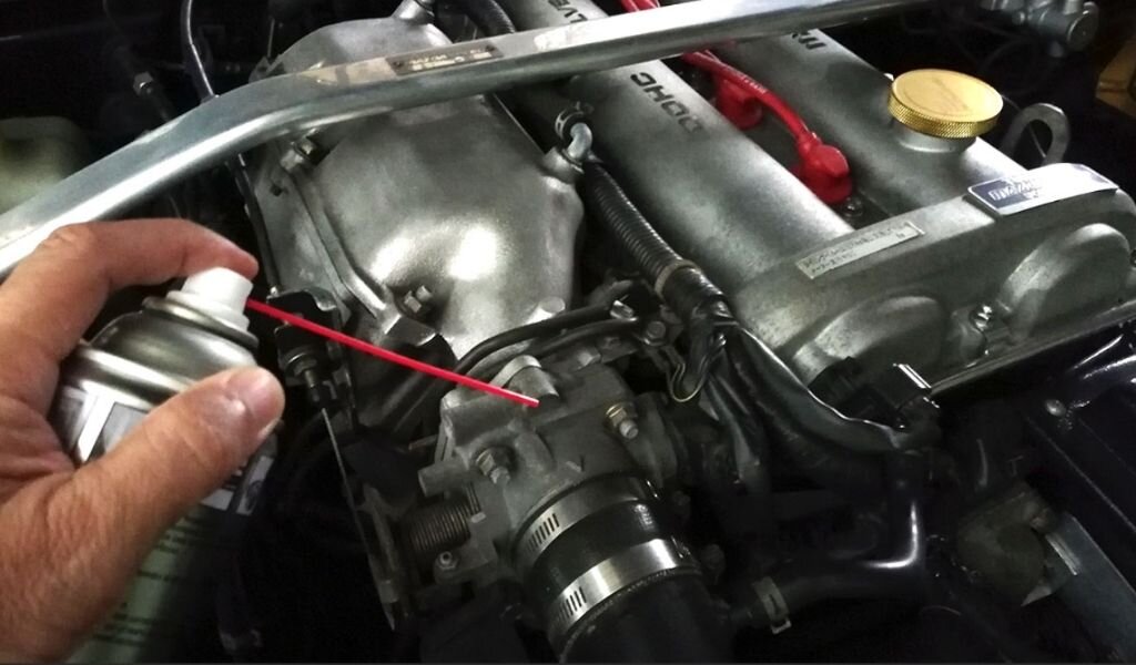 Аккуратно подсунуть носик трубки очистителя карбюраторов под хомут дросселя и полотно прижать что бы не создать подсос воздуха.