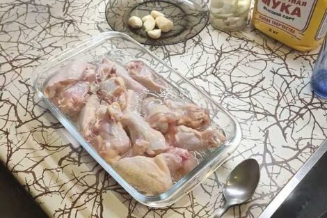 Крылья выкладываем в емкость, заливаем маслом, добавляем воду