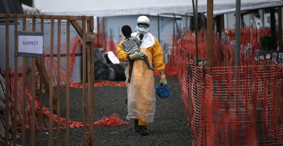 Член организации "Врачи без границ" (MSF) несет ребенка с подозрением на Эболу, 5 октября 2014 года, Либерия. Фото John Moore/Getty Images