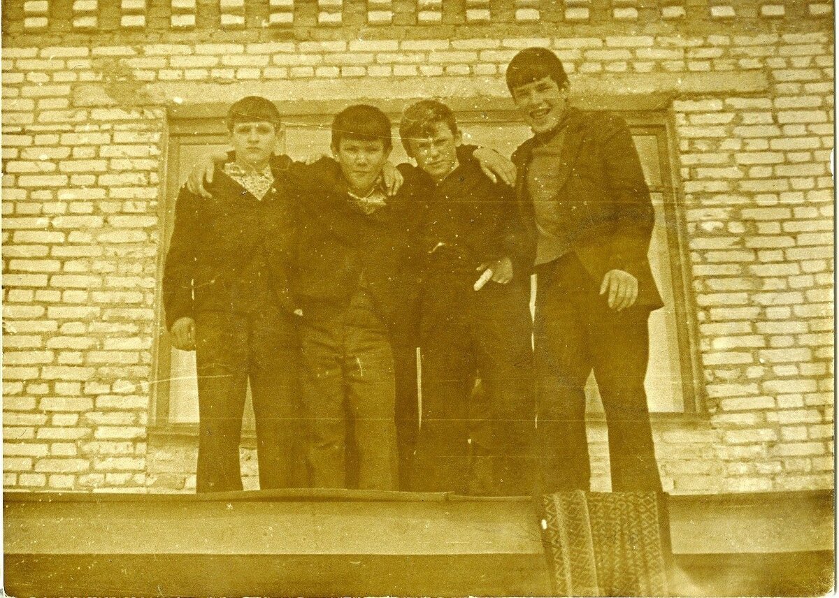 Пацаны на козырьке у входа в детский дом. За спинами  окно спальни на втором этаже. Сбоку свисает дорожка. Мы тоже так делали, сначала выкидывали ее на крышу и трясли прямо сверху. Пока никто не видит! 