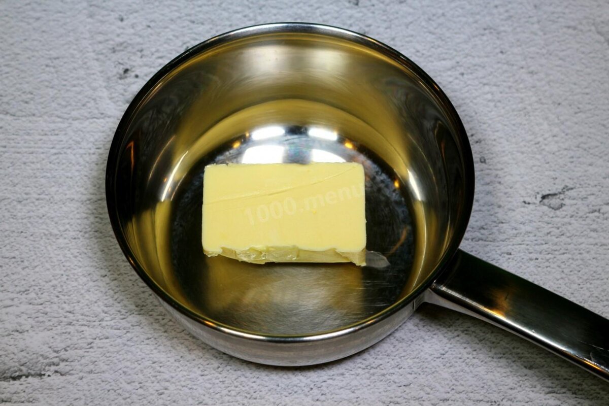 Возьмите сотейник и положите в него кусок сливочного масла весом 110 грамм. Сотейник с маслом поставьте на медленный огонь и растопите масло. Затем добавьте молоко и продолжайте греть маслянисто-молочную смесь.