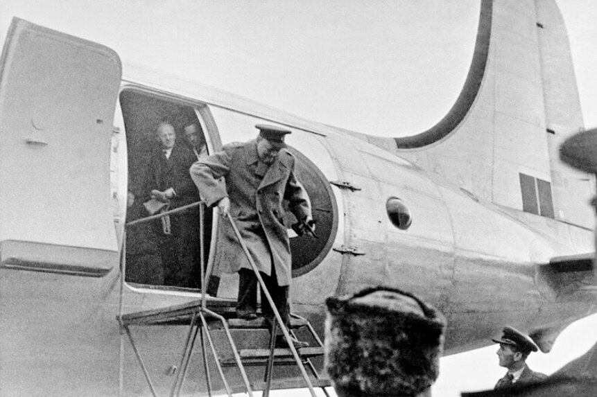Уинстон Черчиль спускается по трапу из своего самолета. Сакский аэродром, 1945 г.