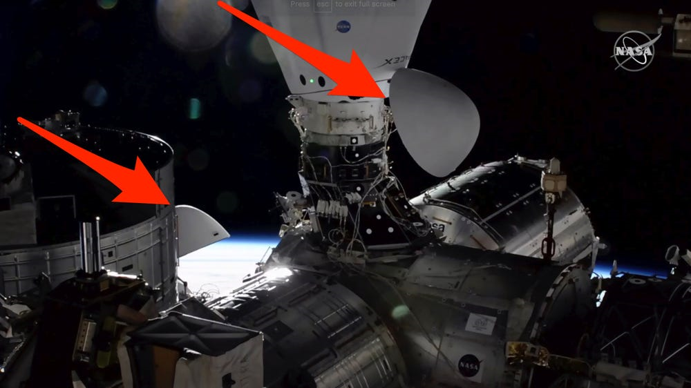 На этом изображении с телевидения НАСА капсула SpaceX Dragon стыкуется с Международной космической станцией (в центре) рядом с капсулой Crew Dragon, которая управляла астронавтами за несколько недель до (слева), 7 декабря 2020 года
