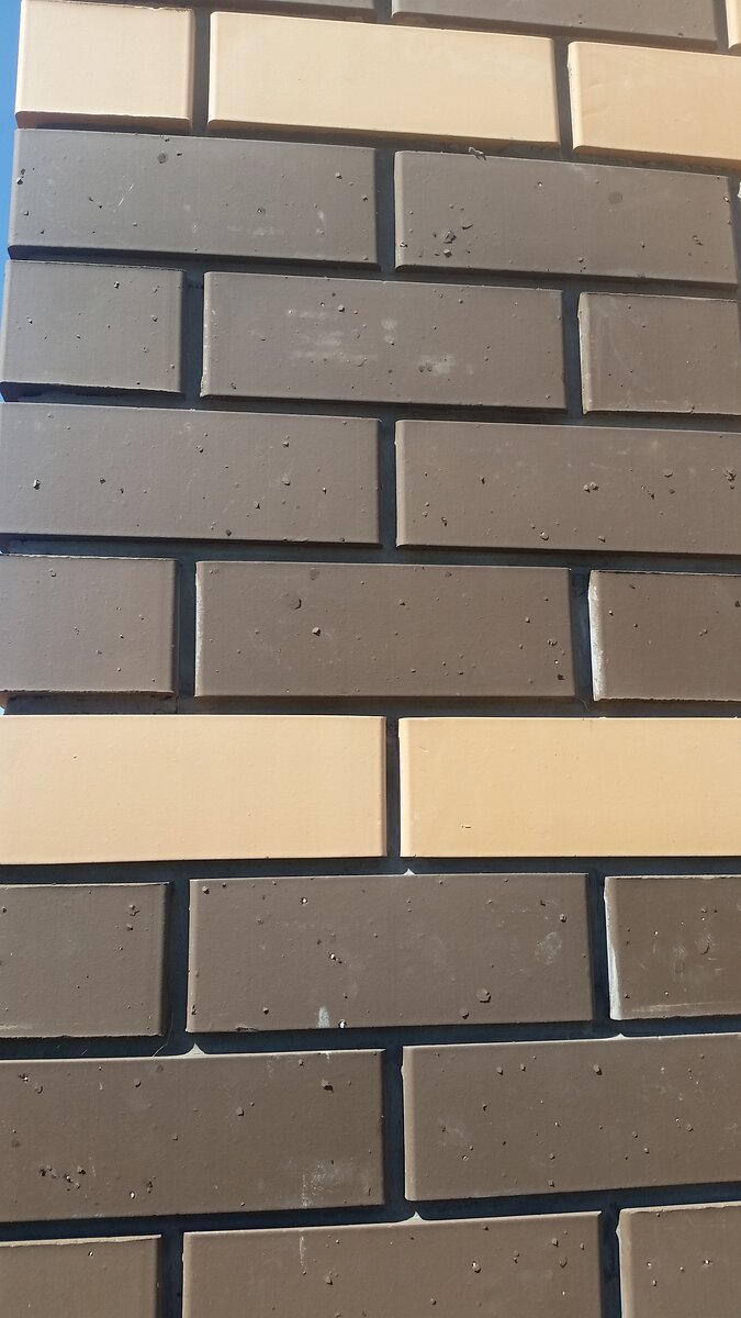 На коричневом кирпиче многократные мелкие вздутия