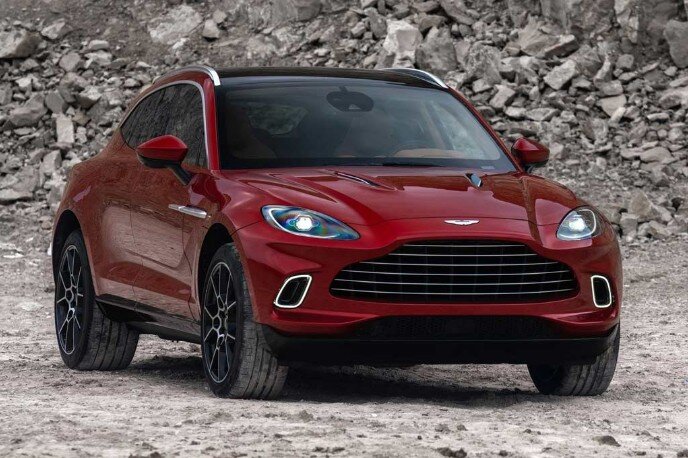 На автосалоне в Лос-Анджелесе 2019 состоялась мировая премьера премиального спортивного кроссовера Aston Martin DBX, призванный составить конкуренцию таким моделям как Bentley Bentayga и Lamborghini Urus. Внешние кузовные панели Астон Мартин ДБХ 2020 изготовлены из алюминия и композитных материалов, при этом автомобиль сразу же привлекает к себе внимание недовольной «мордашкой». Последняя образована широкой «пастью» решетки радиатора и каплевидными фарами. В свою очередь купеобразный профиль внедорожника примечателен 22-дюймовыми колесами, вентиляционными прорезями на передних крыльях, а также стеклянными накладками на стойках кузова, благодаря которым боковое остекление модели кажется цельным. Плюс новая модель Астон Мартин DBX получила «утопленные» дверные ручки, а задний дворник отсутствует — очищение стекла пятой двери происходит за счет «падающего» с крыши потока воздуха. Отказ от этих и некоторых других выступающих элементов позволил сделать облик автомобиля максимально обтекаемым. 