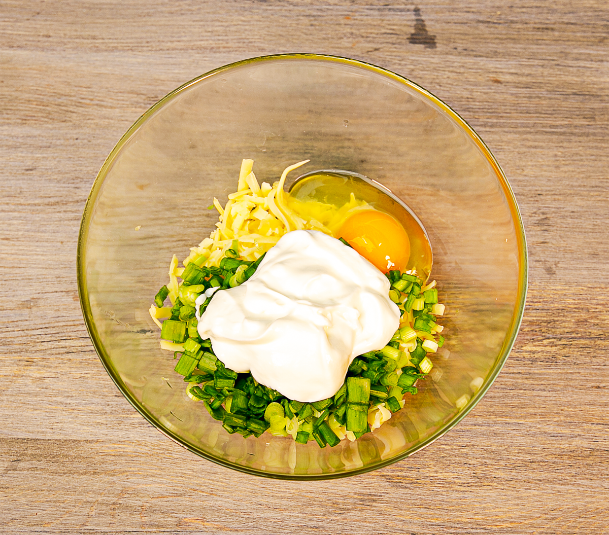 Смешиваем в емкости сыр, сметану, зеленый лук, яйцо, солим и перчим по вкусу.