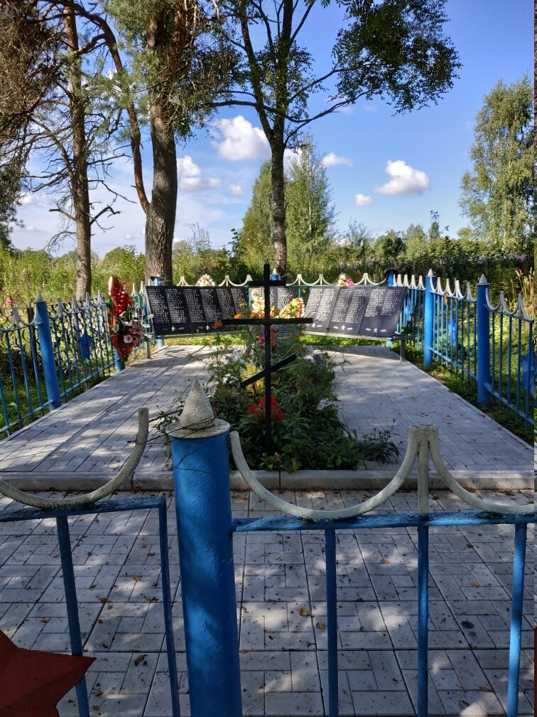 Общий вид братской могилы. На заднем плане памятная доска и списки захороненных, на переднем плане - крест, у которого совершаются православные обряды.