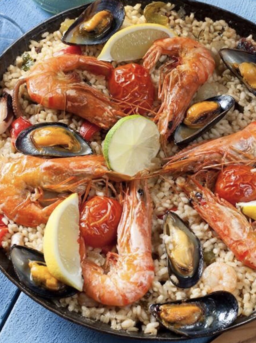 РЕЦЕПТ ПАЭЛЬИ: Ингредиенты: мидии в ракушках - 450 грамм, королевские креветки - 300 грамм, кольца кальмаров - 300 грамм, томатная паста (или тертый свежий томат) - 1 ст. ложка или 1 средняя штука, чеснок - 3 зубчика, листья шафрана или сухой шафран - 1чайная ложка, белое сухое вино - 100 грамм, оливковое масло - 50 грамм, рис (сорт, который не разваривается - можно для ризотто) 0,5 кг. ПРИГОТОВЛЕНИЕ: 1. Сварить мидии в ракушках в подсоленной воде, при кипении добавить белое вино, откинуть мидии на дуршлаг. 2. В казане или в глубокой сковороде с толстыми стенками на оливковом масле пожарить очищенные креветки и кольцами кальмаров, откинуть на дуршлаг к мидиям, когда они зарумянятся. 3. В это же масло кинуть очищенные дольки  чеснока, добавить шафрану томатную пасту или протертую помидору, немного притушить. 4. Всыпать в эту смесь сухой рис (его не мыть и не мешать!) и залить его бульоном от мидий. Закрыть крышкой, довести до готовности. Бульон должен закрывать рис и быть выше его уровня на два пальца в горизонтальном положении. 5. Когда рис приготовится, помешать его, добавить готовые креветки и кальмары, сверху уложить готовые мидии. Украсить дольки лайма или лимона. ПРИЯТНОГО АППЕТИТА! 