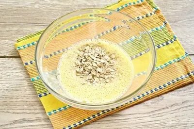 В глубокую миску налейте воду или молоко, вбейте одно яйцо, предварительно размешайте и всыпьте овсяные хлопья.