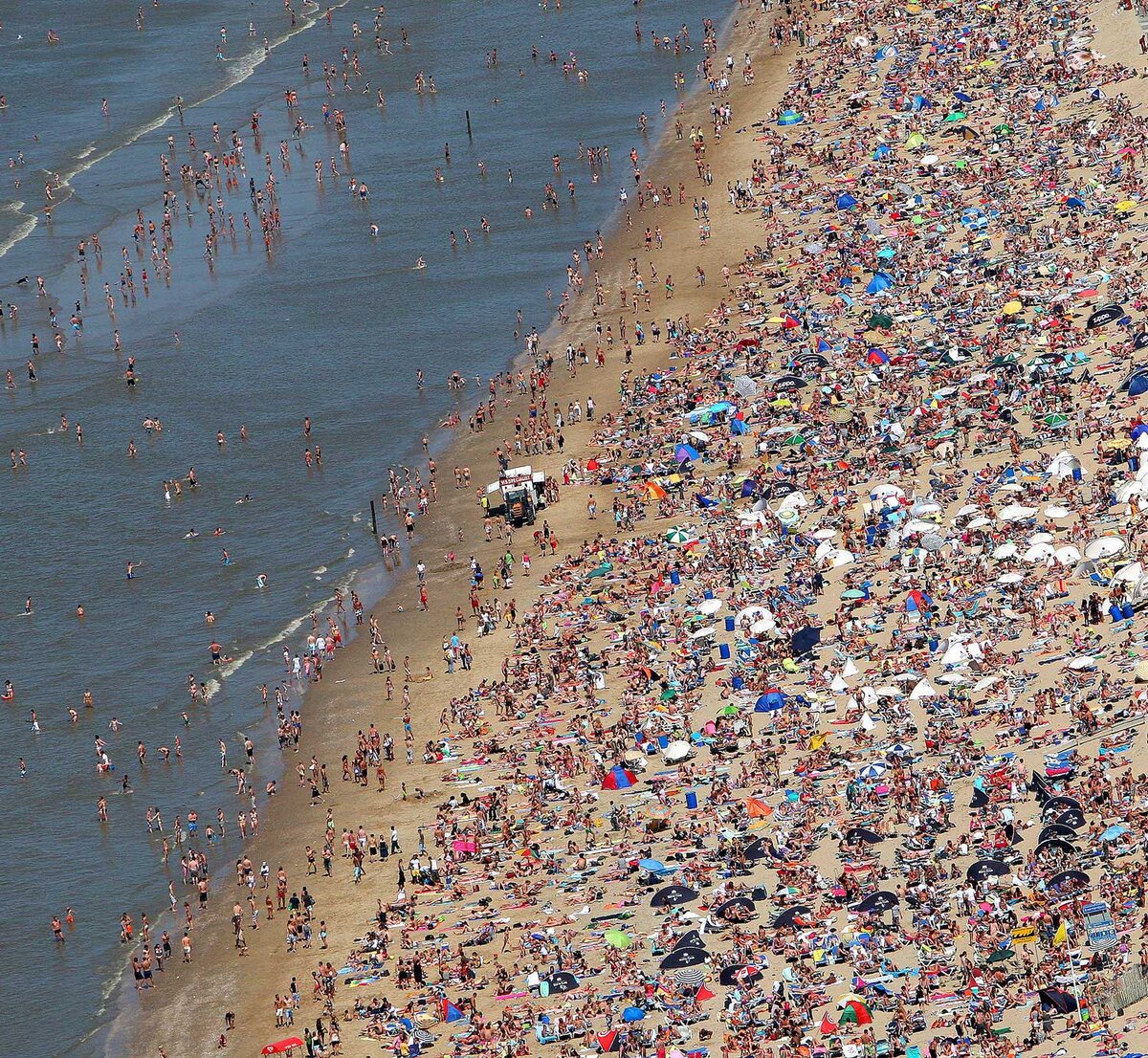 Огромный виднеться. Переполненные пляжи. Куча людей на пляже. Много людей на пляже. Куча народу на пляже.