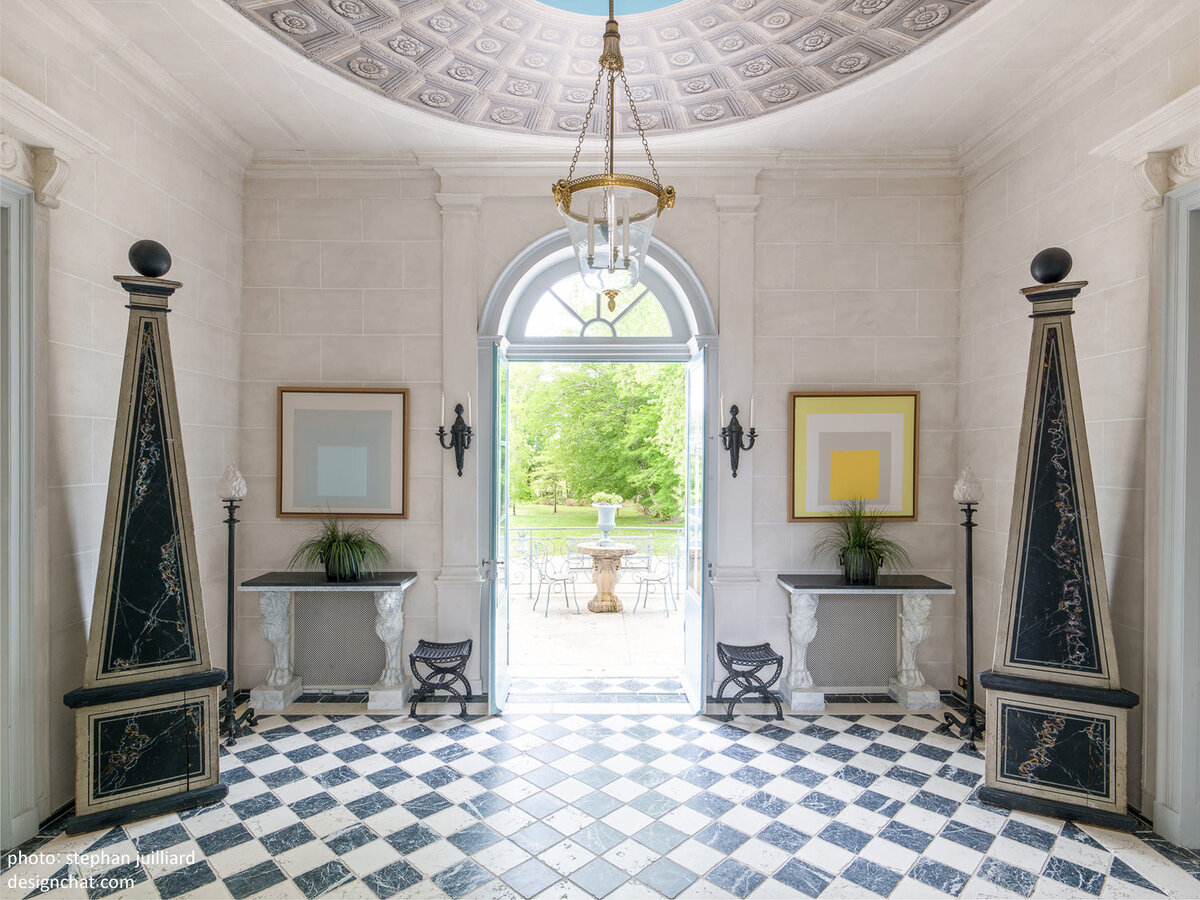 Входной холл замка Fourcas-Hosten в Бордо, дизайнеры Михаэл Коренгел и Жан-Пьер Кальваграк. Пол выложен старинными мраморными плитами в традиционном для XVIII века шахматном порядке. Колонны XVIII века, светильник – XIX века, но в стиле Людовика XVI. На стене пара вставленных в рамки платков Hermès по дизайну Джозефа Альберса. Потолок украшен ручной росписью.