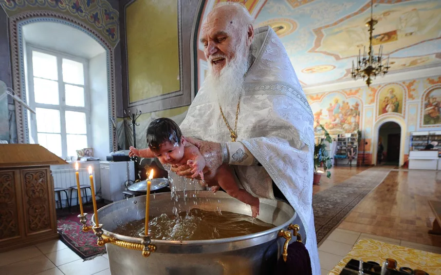 Крестит детей священник