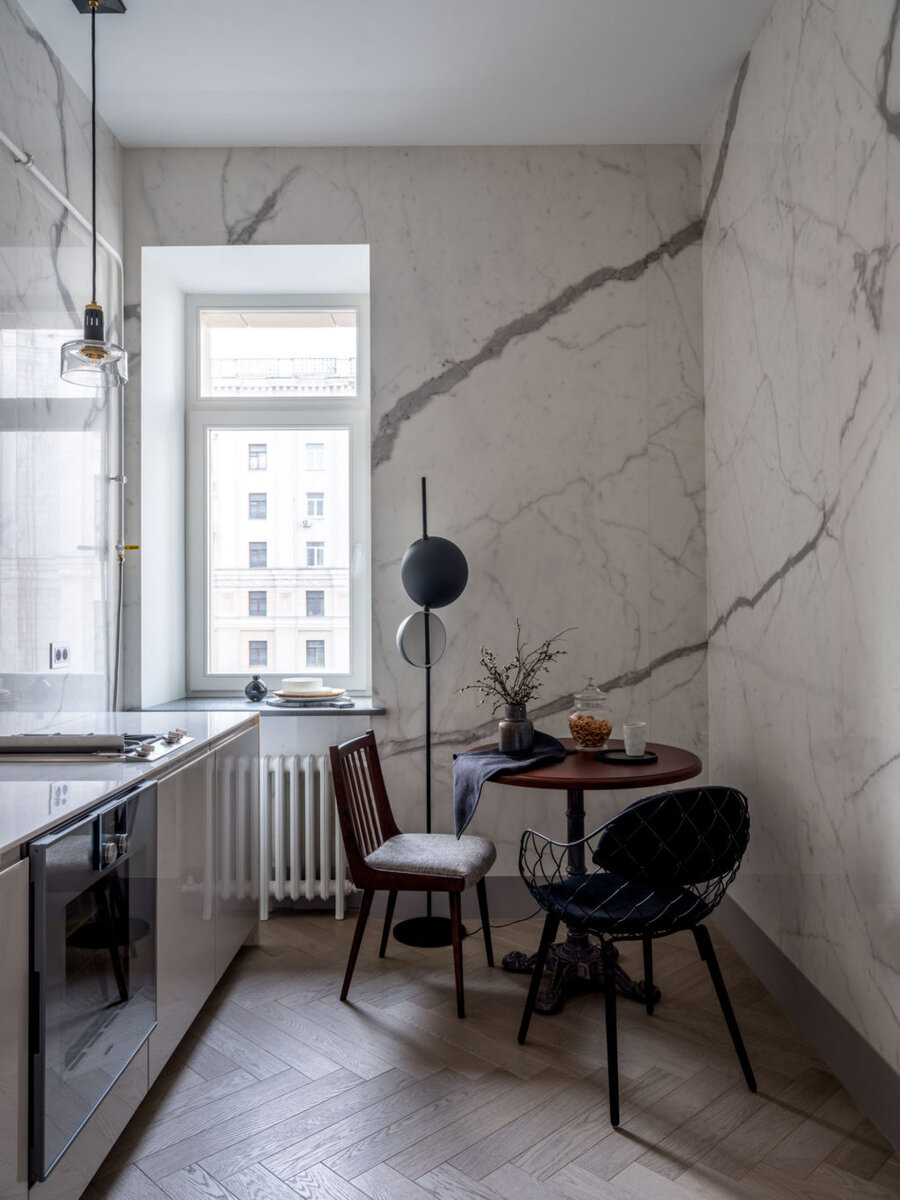 Квартира по дизайну Ольги Тищенко. Стены кухни облицованы керамогранитом, Ariostea. Ольга подбирала плитки так, чтобы получился цельный рисунок — это зрительно делает комнату больше. Кухонный гарнитур, Nobilia; торшер, Oluce; у стола из магазина “Ресторация” винтажный стул и кресло, Magis. На полу паркет, Finex.