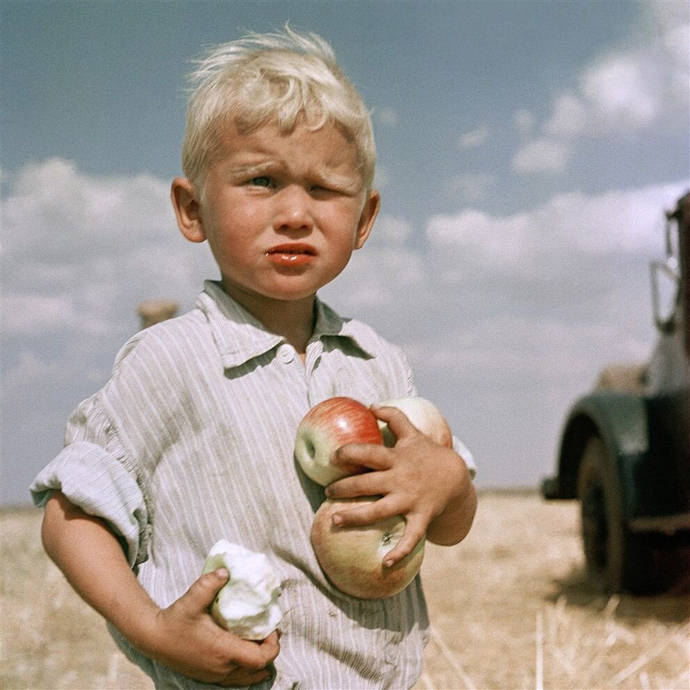 Фото Юрия Абрамочкина. Целина, Кустанайская область. 1962 год. "А мальчик с яблоками – это внук председателя. Помню, увязался он за нами, а у меня сразу глаз зацепился за то, что он белобрысенький такой, под пшеницу окрашенный. И яблоко жует. Хитрость раскрою – два яблока я ему дал, чтобы в кадре было несколько." Ю.Абромочкин