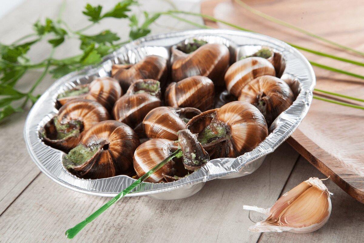 Улитки в соусе по-бургундски — изысканное блюдо со смесью масла, чеснока и петрушки. Для любителей средиземноморской кухни.