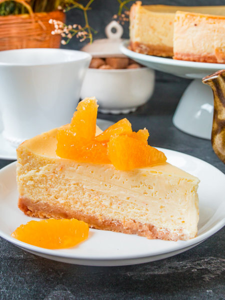 Готовим основу.  Печенье размалываем в крошку при помощи блендера. Добавляем растопленное масло и перемешиваем.
Перекладываем в разъемную форму и утрамбовываем по дну (бортики делать не нужно).
Отправляем форму в разогретую до 160 градусов духовку и выпекаем в течение 10 минут.
Вынимаем и остужаем
Соединяем сливочный сыр, сахар, апельсиновый сок (должно получиться около 120 мл), крахмал и цедру (1 ст.л.).
Смешиваем венчиком до однородного состояния.
По одному добавляем яйца, хорошо перемешивая до однородности. Вливаем сливки и снова перемешиваем.
Вливаем крем в форму с основой.
Ставим форму в разогретую до 160 градусов духовку, на дне которой уже стоит форма с кипятком.
Выпекаем чизкейк около часа.
Очень важно не передержать чизкейк в духовке, иначе при охлаждении он может треснуть.
Определить готовность торта довольно легко – постучите ложкой по борту формы: у готового чизкейка должна подрагивать только середина (5-6 см в центре).
Готовый чизкейк оставляем на 40 минут в выключенной приоткрытой духовке, затем вынимаем и даем остыть при комнатной температуре. После этого ставим в холодильник на 4 часа, а лучше на ночь.
Перед подачей проводим ножом вдоль стенок формы, снимаем бортик и перекладываем чизкейк на блюдо.
Дальше нужно вырезать филе из апельсина.
Для этого срезаем с него кожуру вместе с белыми пленками. И вырезаем сегменты.
Подаем чизкейк с филе апельсина.
Если апельсины кисловаты, предварительно посыпаем их сахарной пудрой.    Ингредиенты:   на форму 21 см Основа
сахарное печенье 170 грамм
сливочное масло 80 грамм

Начинка: 
сливочный сыр 700 грамм
апельсин крупный 1 шт.
сахар 150 грамм
кукурузный крахмал 30 грамм
яйца 3 шт.
сливки 33% 150 мл.                                 Приятного аппетита!