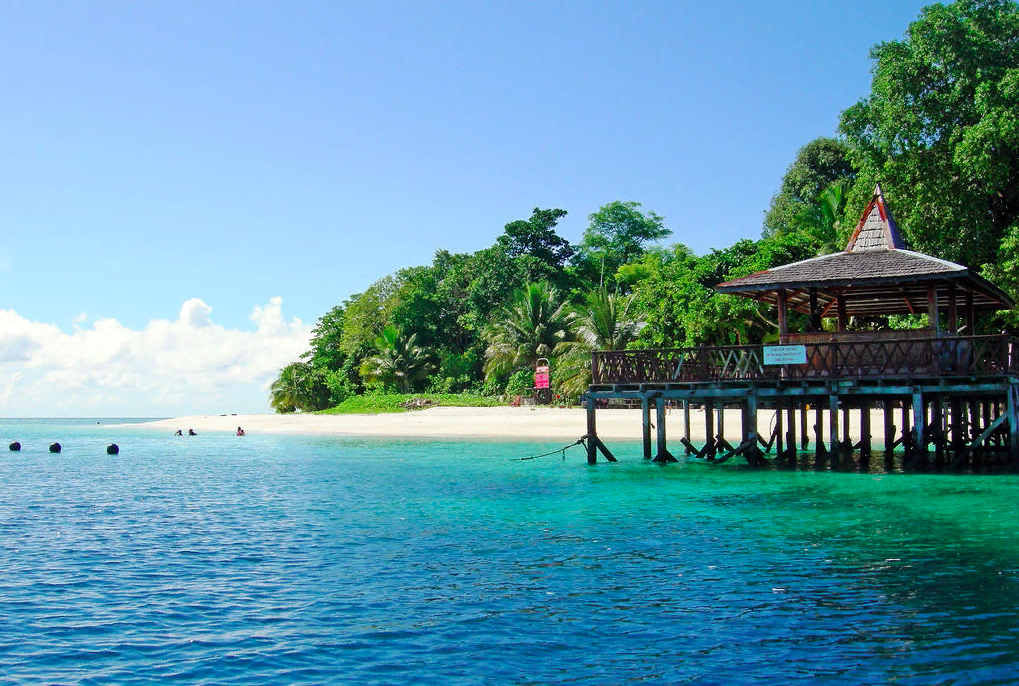 Малайзия у нас ассоциируется с островом Борнео, который является настоящей легендой. Ведь с ним неразрывно связаны многочисленные пиратские истории. Здесь царит потрясающая атмосфера, которая придает отдыху особое настроение. Поверьте, что отпуск на Борнео (Малайзия) вам запомнится надолго. Место расположения Остров Борнео (Малайзия) имеет еще одно название - Калимантан, а находится он в самом центре Малайского архипелага на территории юго-восточной Азии. Остров является по-своему уникальным местом. Дело в том, что территория Борнео поделена между тремя государствами – Малайзией, Индонезией и Брунеем. Общая площадь острова составляет более 743 тысяч кв. км. Наибольшая часть принадлежит Индонезии. А территория Малайзии составляет порядка 200 тысяч кв. км. Она разделена на две провинции - Саравак и Сабах, которые граничат с Брунеем и Индонезией. Побережье Борнео омывается Южно-Китайским морем, а также морями Сулавеси, Яванским и Сулу, проливами Макасрским и Каримата. Неподалеку находится остров Ява, Суматра и Филиппинские острова. Борнео имеет гористый рельеф, самая высокая точка – это гора Канабалу, ее высота 4095 метров. Большая часть острова покрыто зарослями джунглей, в которых обитают дикие животные. Малайзия, Борнео – это отличный пример страны с потрясающе высоким уровнем жизни. Столицей острова является город Кота Кинабалу. Как добраться до Борнео (Малайзия) Добраться до Борнео не так-то и просто, для этого придется воспользоваться авиасообщением. Есть два ближайших аэропорта, от которых можно добраться до острова. Один из них находится неподалеку от города Кота Кинабалу в штате Сабах, а второй – в Куала-Лумпуре. Из аэропорта до городов можно доехать на такси (при аэропортах созданы специальные службы такси). Между собой штаты и города связаны авиарейсами компании «Малайзия Эиерлайнс». Такие перелеты очень востребованы не только среди туристов, но и у местных жителей. Кроме того, по самому острову ходят поезда и автобусы. Также имеется и морское сообщение. Так, в Кота Кинабалу приходят паромы из Брунея и Лабуана. Кроме того, в город заходят большие круизные лайнеры. Климат и погода Борнео Туристов больше всего интересует пляжный отдых на Борнео (Малайзия), а значит, перед поездкой стоит узнать, какая погода вас ожидает во время отпуска. Вообще, для острова характерен жаркий, влажный тропический климат. На Борнео нет значительных колебаний годовых температур. В любое время года температурные показатели находятся в пределах - +27-32 градусов. Дожди идут в течение всего года, но все же есть периоды с большей их интенсивностью.Самыми влажными месяцами являются октябрь, ноябрь, май и апрель. Но даже в эти периоды осадки не слишком докучают отдыхающим, поскольку выпадают они, как правило, ночами и кратковременно. Поэтому можно сказать, что на Борнео царит вечное лето, что соответствует экваториальному климату. Но все же наиболее удачными для посещения курорта считаются месяца январь и февраль. Температура воды на острове не слишком отличается от температуры воздуха, поэтому купаться здесь можно всегда.Пляжи Борнео Остров Борнео (Малайзия) привлекает туристов, прежде всего, своими тропическими белоснежными пляжами с богатой растительностью и мелким песком. Большая часть из них защищена коралловыми островами от волн. Между побережьем и коралловыми островами постоянно курсируют лодки, отвозящие туристов покупаться на них. Особенно это актуально во время «красного прилива», когда запрещается входить в море. Запрет введен не просто так. Дело в том, что «красный прилив» – это не что иное, как цветение морской воды. В такие периоды наблюдается массовое размножение планктона, который и окрашивает море в красный цвет. Окунаться в воду в это время действительно очень опасно, поскольку можно стать жертвой токсического отравления. На радость туристам, на острове практически нет пляжей, принадлежащих отелям, поэтому можно смело размещаться на любом участке побережья и нежится на горячем песочке. По отзывам туристов о Борнео (Малайзия) можно утверждать, что лучшими пляжами могут похвастаться города Сандакан, Кота Кинабалу и Кучинга. Хотя, все побережье острова красивое и чистое, в отличие от более именитых и известных мировых курортов. Очень приятным бонусом является полное отсутствие волн на местных пляжах. Коралловые рифы надежно защищают побережье от сильных штормов, поэтому серферам здесь делать нечего. Зато морской мир Борнео просто потрясает воображение своей экзотикой. И все же самым лучшими пляжами можно насладиться на территории морского парка Тунку Абдул Рахман, в состав которого входит пять маленьких островов. Оплатив поездку сюда, можно посетить сразу все острова и заняться дайвингом. Острова имеют минимальную инфраструктуру – кафе, душевые, раздевалки, туалеты и прочее. Отдыхать на них приезжают не только туристы, но и местные жители. Потрясающе прозрачное море и чистый песок – лучшее место для отдыха.