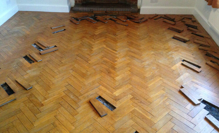 Если паркет лежит на фанере, то справиться можно и без разборки участков, с помощью саморезов.