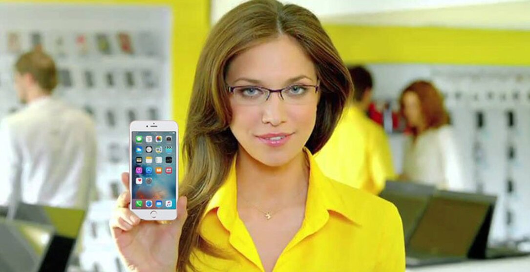 Девушка из рекламы держит в руке iPhone 6S на 32GB в Евросети