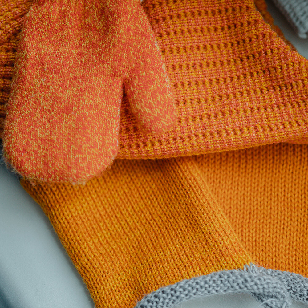 Пряжа — полушерсть. Образец слева — "канарейка" + "тыква", образец справа — "тыква". Сверху варежки и шапка из магазина.