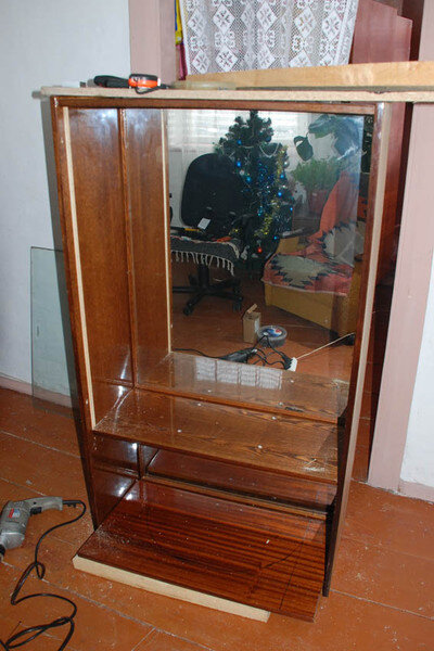 Взяли верхнюю, зеркальную часть, вынули стекла и стеклянную полку, поставили его на бок.

