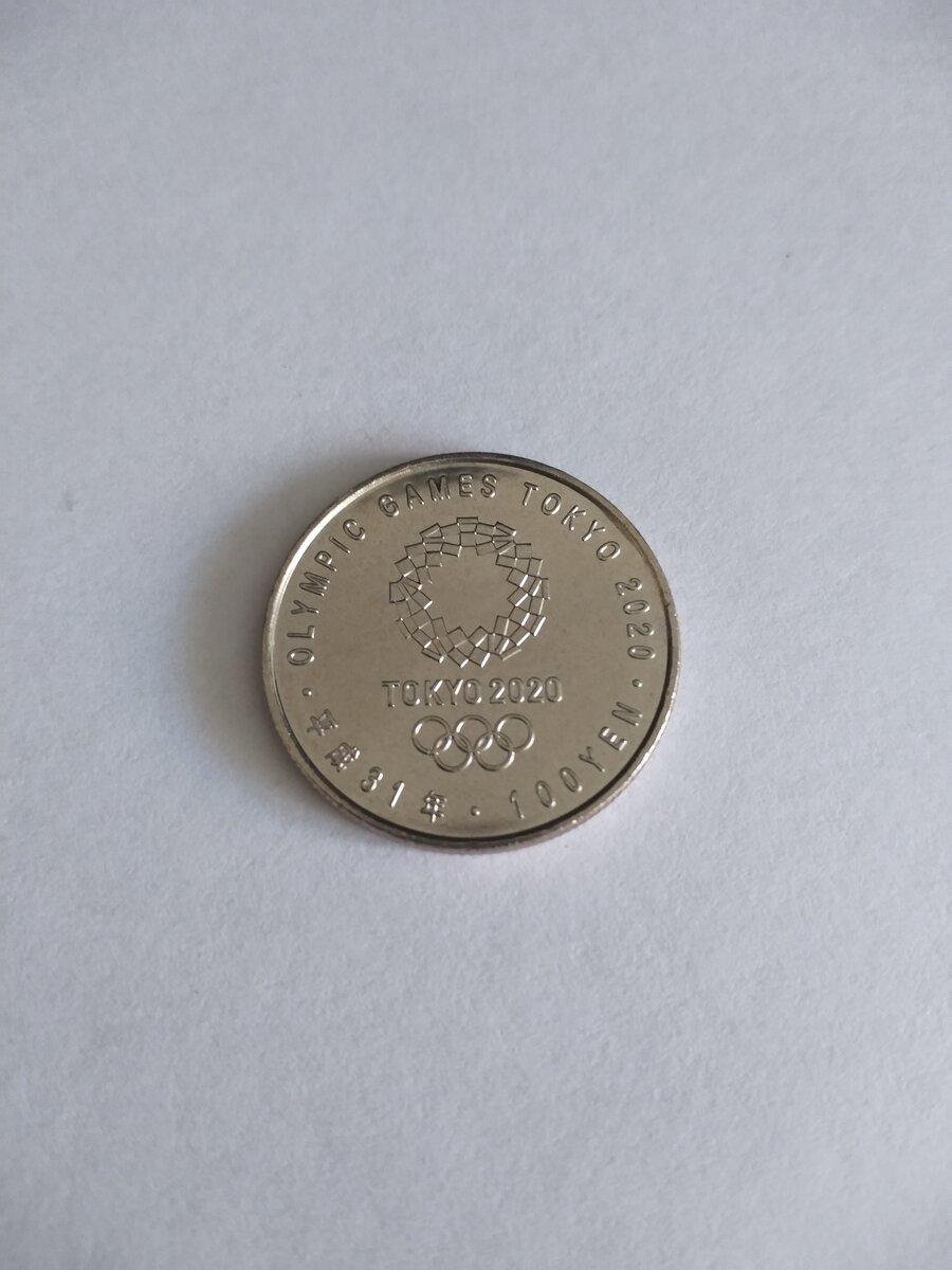 На аверсе изображена эмблема игр, номинал монеты и год выпуска монеты по японскому летоисчислению.