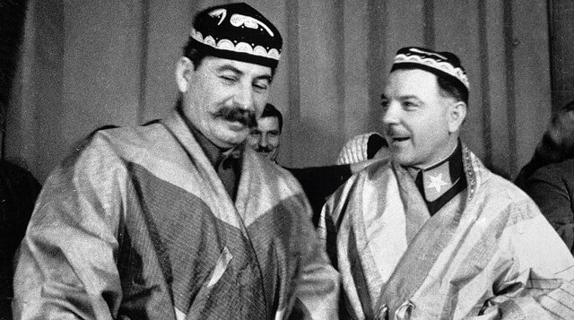 ÐÐ¾ÑÐ¸Ñ Ð¡ÑÐ°Ð»Ð¸Ð½ Ð¸ ÐÐ»Ð¸Ð¼ÐµÐ½Ñ ÐÐ¾ÑÐ¾ÑÐ¸Ð»Ð¾Ð² Ð² Ð½Ð°ÑÐ¸Ð¾Ð½Ð°Ð»ÑÐ½ÑÑ ÐºÐ¾ÑÑÑÐ¼Ð°Ñ, Ð¿Ð¾Ð´Ð°ÑÐµÐ½Ð½ÑÑ Ð¸Ð¼ Ð´ÐµÐ»ÐµÐ³Ð°ÑÐ°Ð¼Ð¸ - ÑÑÐ°ÑÑÐ½Ð¸ÐºÐ°Ð¼Ð¸ ÑÐ¾Ð²ÐµÑÐ°Ð½Ð¸Ñ Ð¿ÐµÑÐµÐ´Ð¾Ð²ÑÑ ÐºÐ¾Ð»ÑÐ¾Ð·Ð½Ð¸ÐºÐ¾Ð² Ð¢ÑÑÐºÐ¼ÐµÐ½Ð¸Ð¸ Ð¸ Ð¢Ð°Ð´Ð¶Ð¸ÐºÐ¸ÑÑÐ°Ð½Ð°, 1935 Ð³Ð¾Ð´