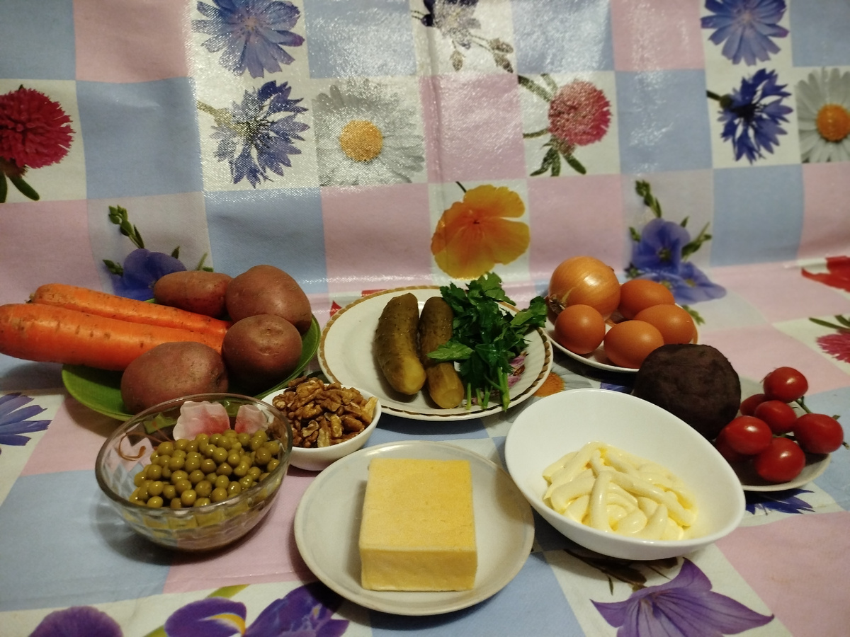 Нам потребуется: 2 солёных или маринованных огурца, 4 картофелины, 2 морковки, 1 свекла, 1 луковица, 4 яйца, 150 г сыра, 70 г ядер грецких орехов, зелёный горошек 350 г, майонез 250 г, помидоры черри и петрушка для украшения.